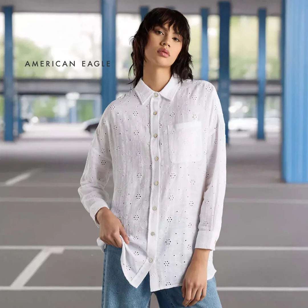 American Eagle Loose Fit Eyelet Shirt in white, featuring button-down design and a front pocket, styled in a modern setting.