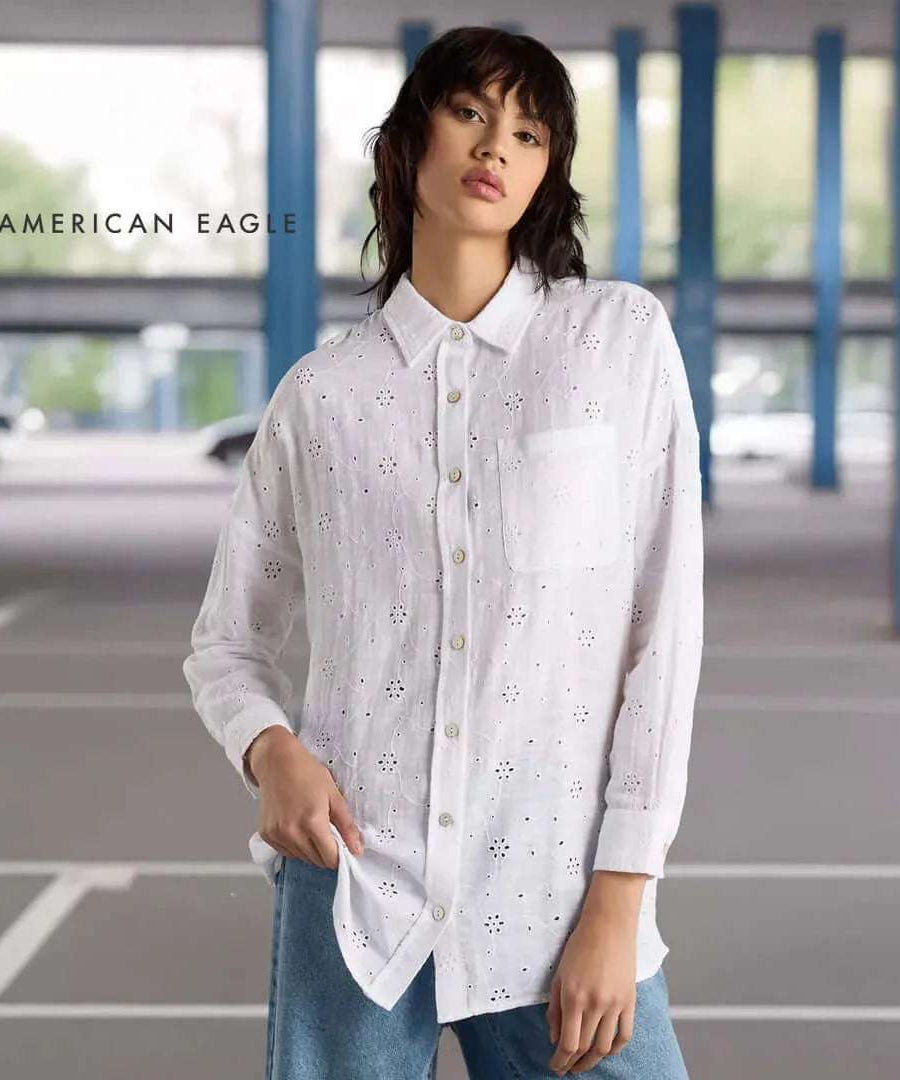 American Eagle Loose Fit Eyelet Shirt in white, featuring button-down design and a front pocket, styled in a modern setting.